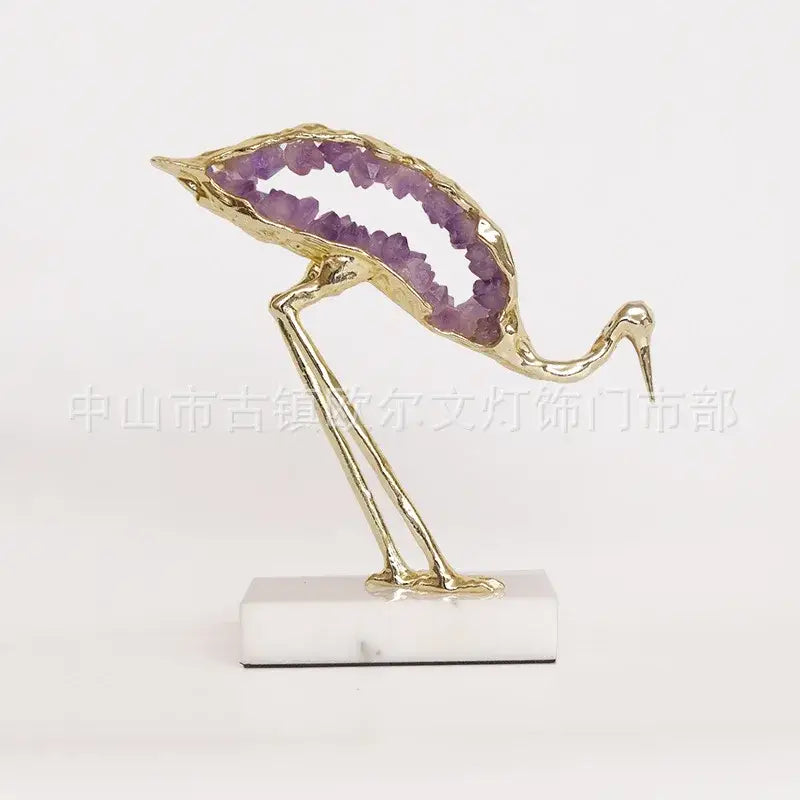 Gold-toned decorbites crystal crane sculpture with hollow body filled with purple amethyst on white marble base