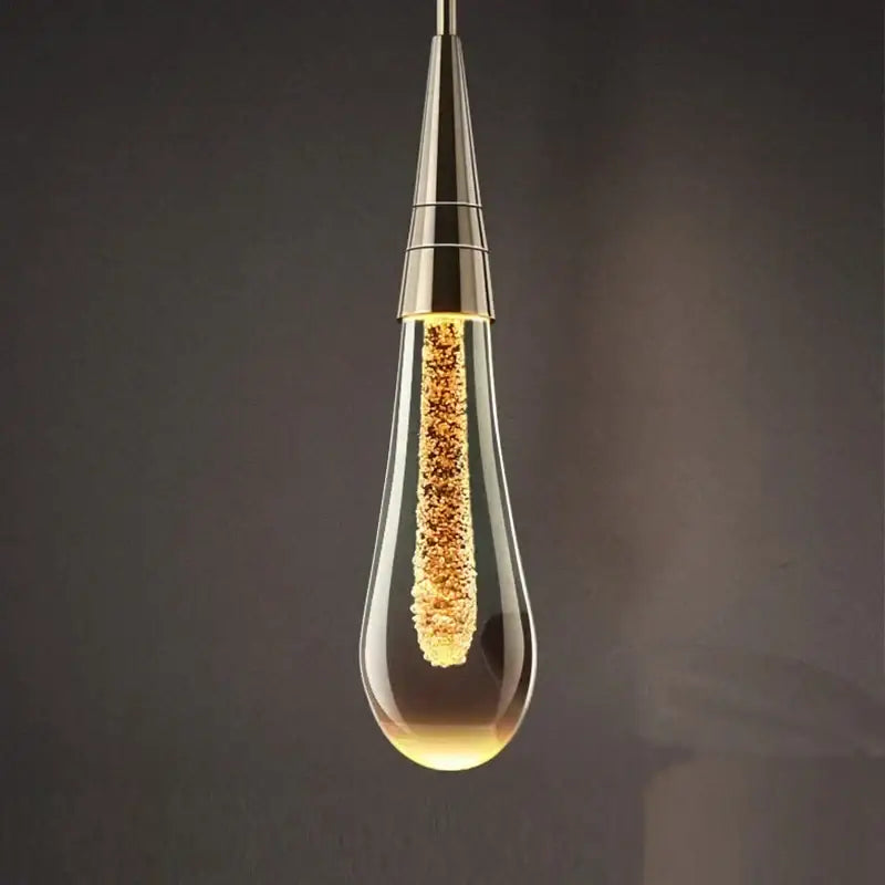 Decorbites crystal drop chandelier featuring a gold glass teardrop pendant light with golden filament strands for dining rooms