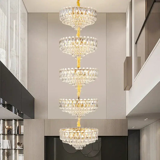 A multi-tiered decorbites crystal duplex chandelier with a golden frame and clear glass prisms for living room lighting