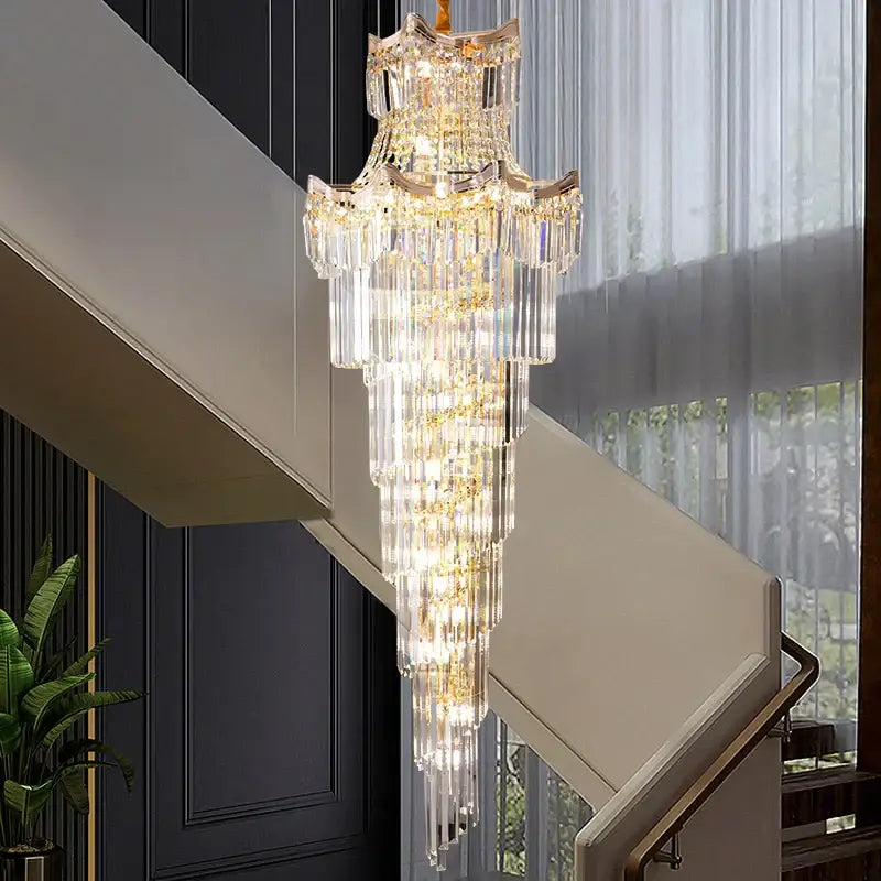 A decorbites crystal duplex chandelier with cascading clear glass prisms and gold accents above a staircase