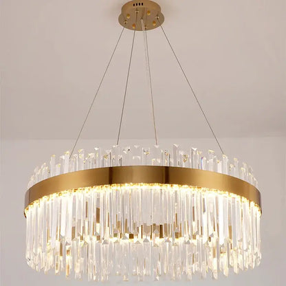 A modern decorbites crystal led chandelier with gold metal frame and cascading clear crystal prisms for dining room lighting