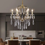 Elegant gold-toned decorbites crystal led chandelier with clear crystal droplets hanging above modern dining table