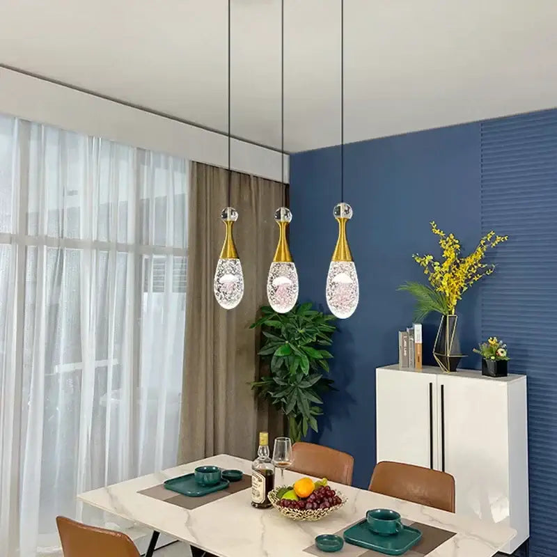 Three elegant gold-toned decorbites crystal led pendant lights with teardrop glass shades for dining room lighting