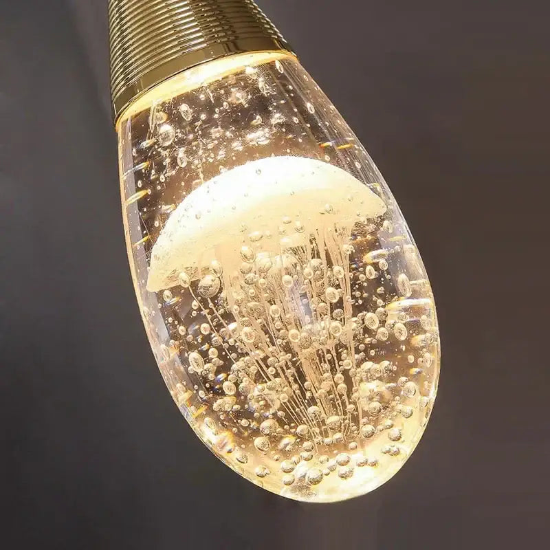 A golden-toned decorbites crystal led chandelier pendant light with a teardrop glass body and illuminated jellyfish design
