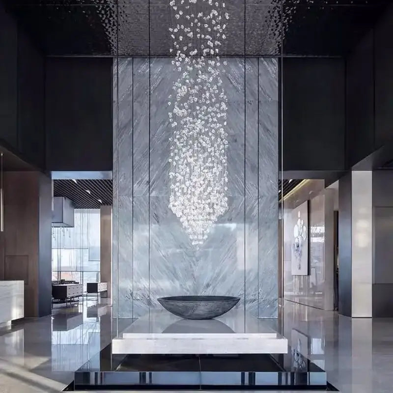 A decorbites crystal led chandelier with clear faceted crystals cascading above a dark gray stone bowl on marble pedestal