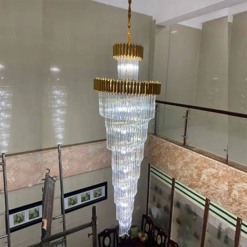 A decorbites crystal led multi-layer staircase chandelier with cascading clear crystal prisms and gold-toned frame