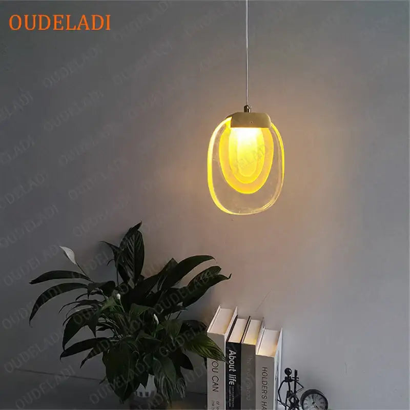A decorbites crystal led pendant with a warm yellow glow, oval glass shade, and sleek metallic top for kitchen use