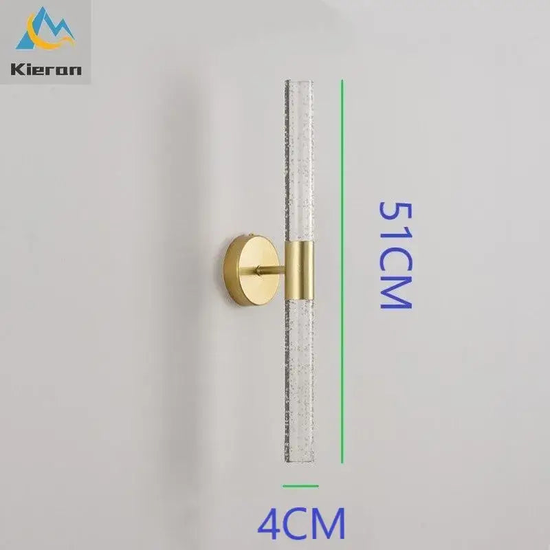 Gold-toned decorbites crystal led wall lamp with clear textured glass cylinder and circular brass base for bedroom decor