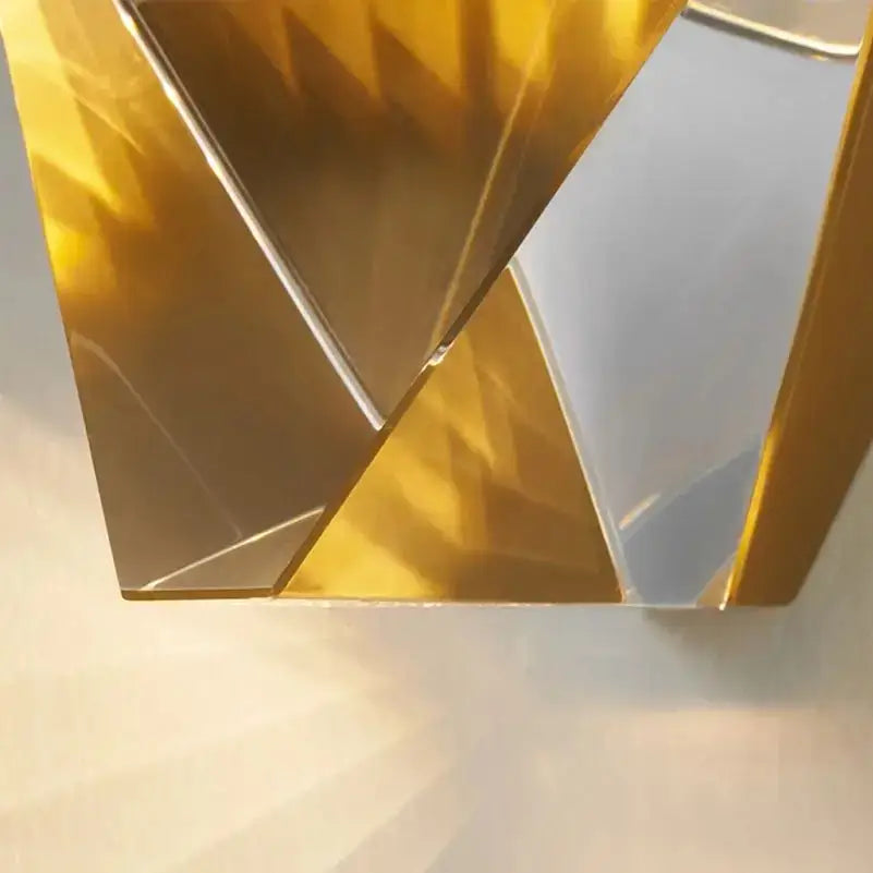 Modern gold crystal led wall sconce featuring a golden geometric mirror with angular faceted surfaces reflecting light