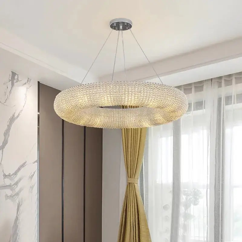 A modern luxury crystal loft chandelier with chrome base and clear crystal beads emitting a warm glow for living room decor