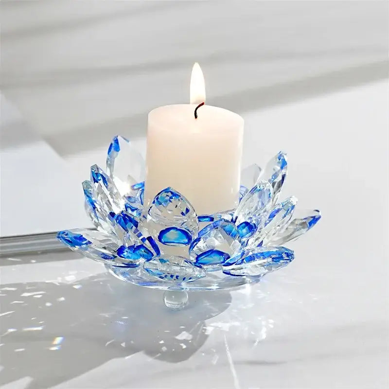 A translucent blue and clear glass lotus candle holder with faceted petals cradling a white pillar candle