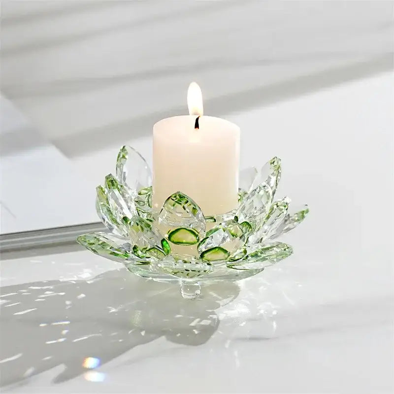 A clear green-accented crystal lotus candle holder with faceted petals holding a white pillar candle for aromatherapy