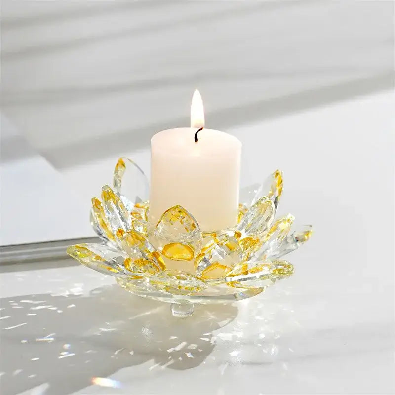 A clear faceted crystal lotus candle holder with golden accents holding a white pillar candle for aromatherapy use