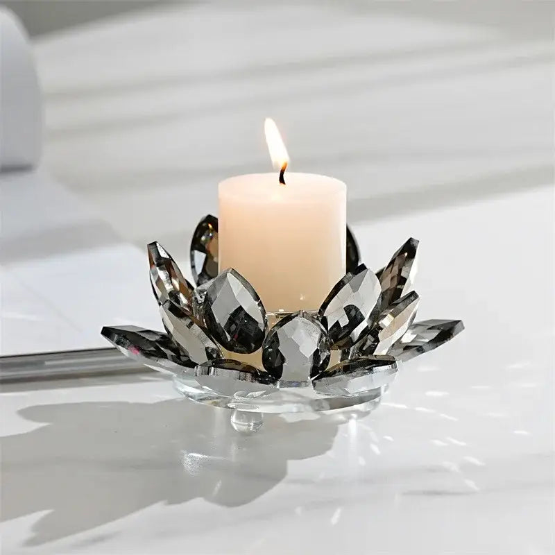 A sleek dark crystal lotus candle holder with faceted petals holding a lit white pillar candle for aromatherapy