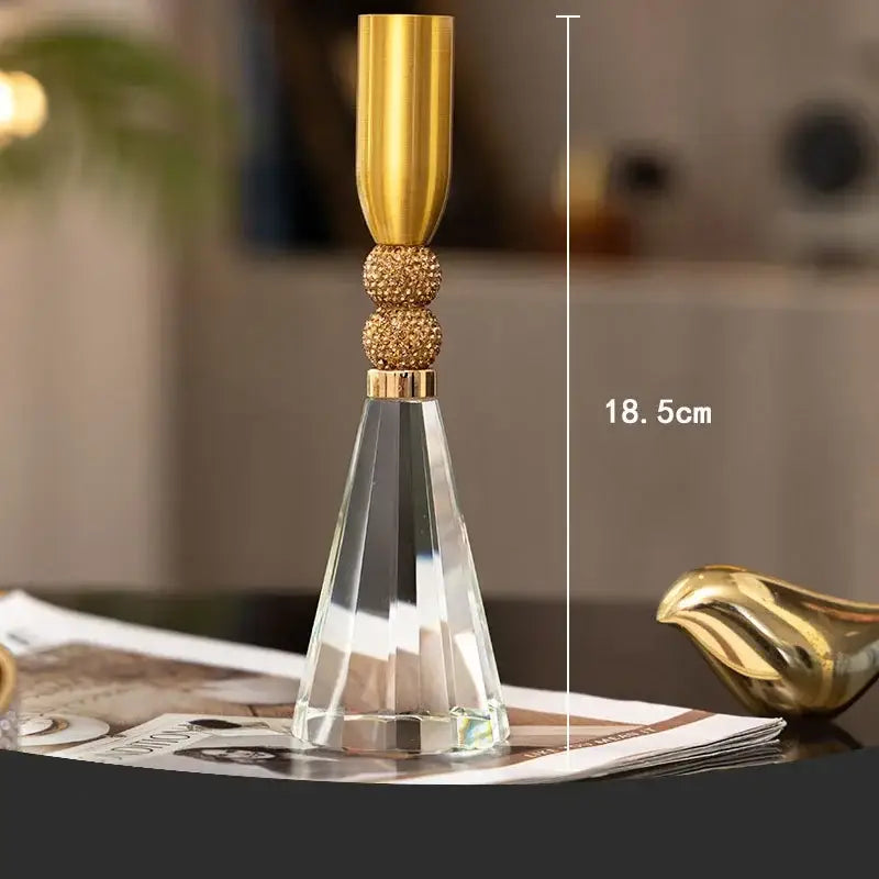 Elegant gold and crystal lotus candle holder with polished metallic top and textured spheres on faceted crystal base