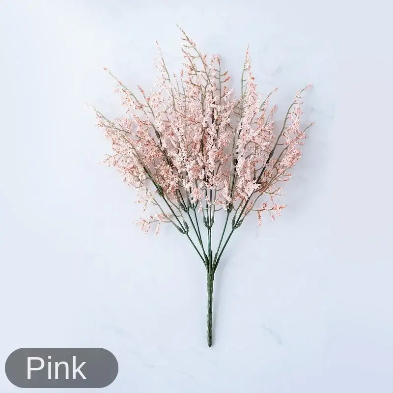 A delicate pink artificial flower arrangement with slender blossoms in a mint green ceramic vase with lemon grass branch