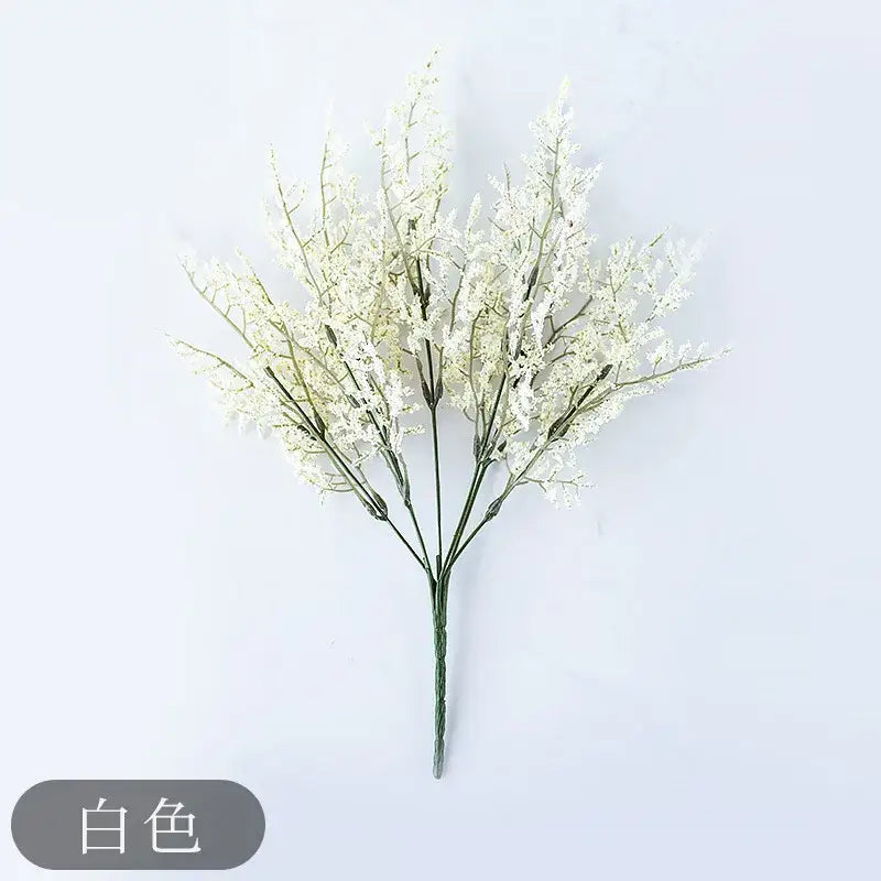 White artificial flower bouquet with delicate blooms in mint green ceramic vase with lemon grass branch for living room