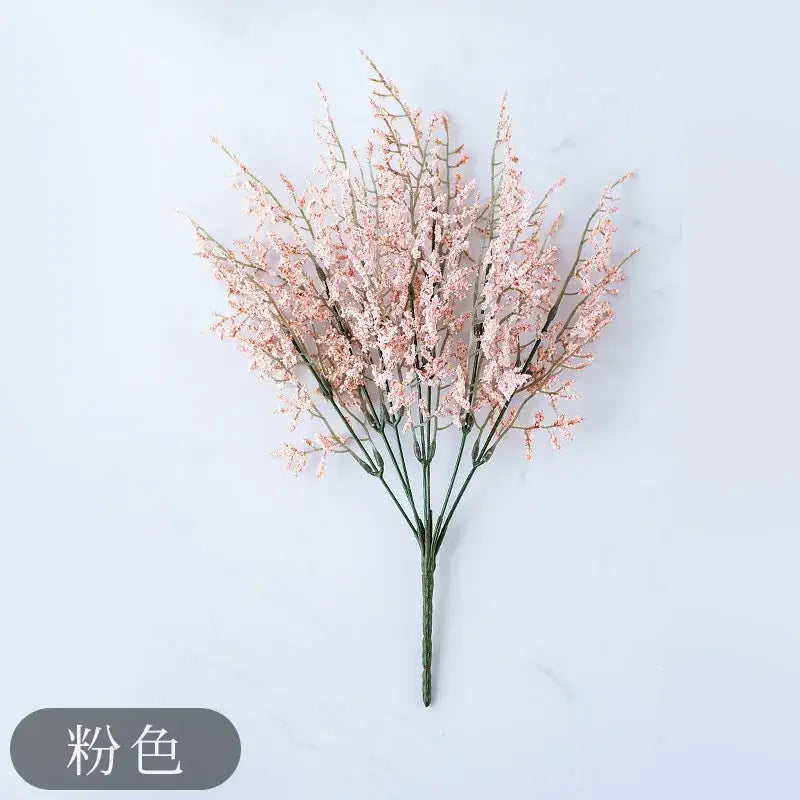 Mint green ceramic vase with delicate pink artificial flowers and a slender yellow lemon grass branch for living room decor