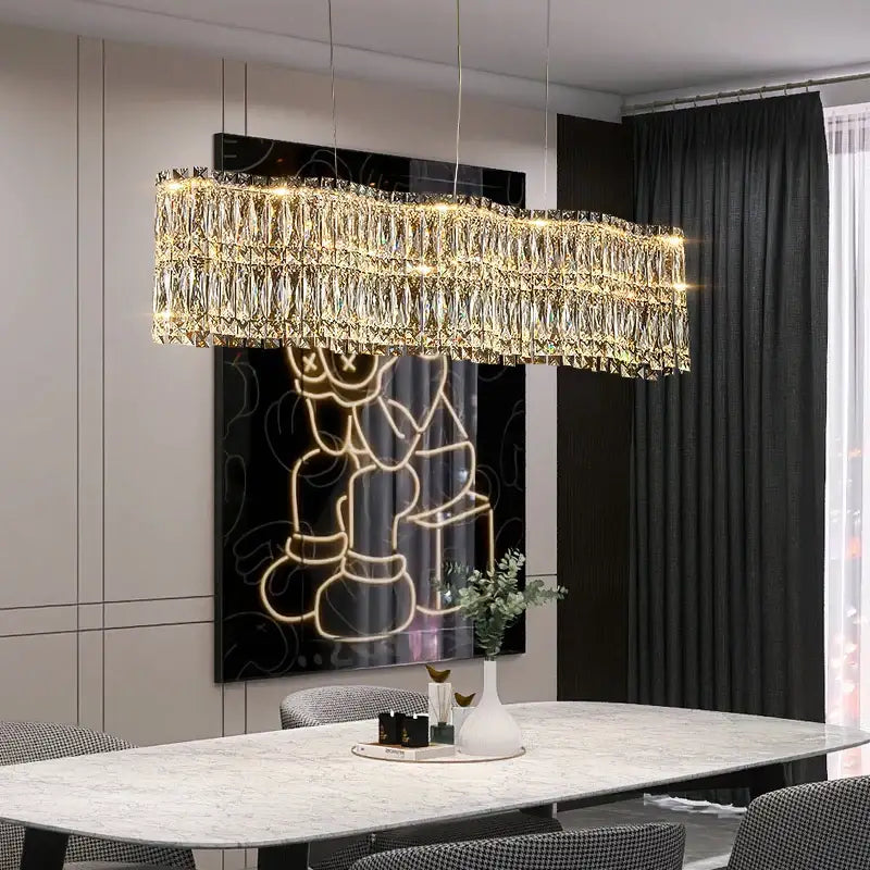 A modern rectangular decorbites crystal luxe chandelier with cascading golden crystal prisms above a dining table