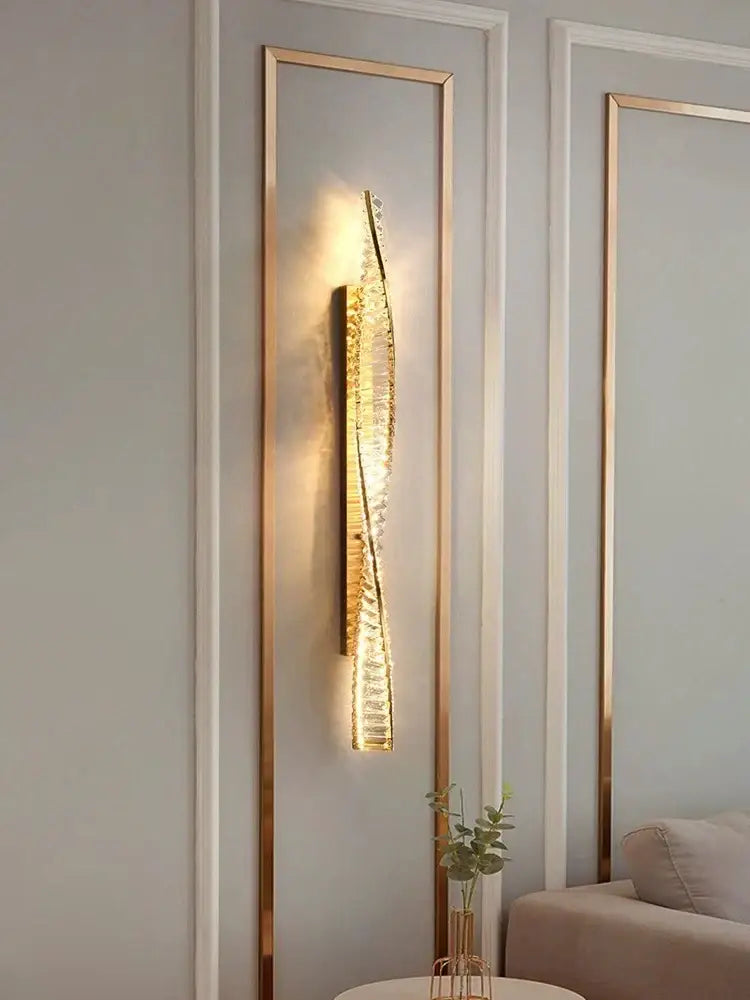 A sleek gold-toned crystal luxe wall sconce with textured crystal design emitting warm bedroom lighting