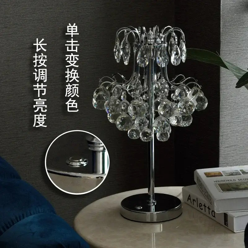 A decorbites crystal table lamp with polished chrome base and clear faceted glass droplets for bedroom lighting