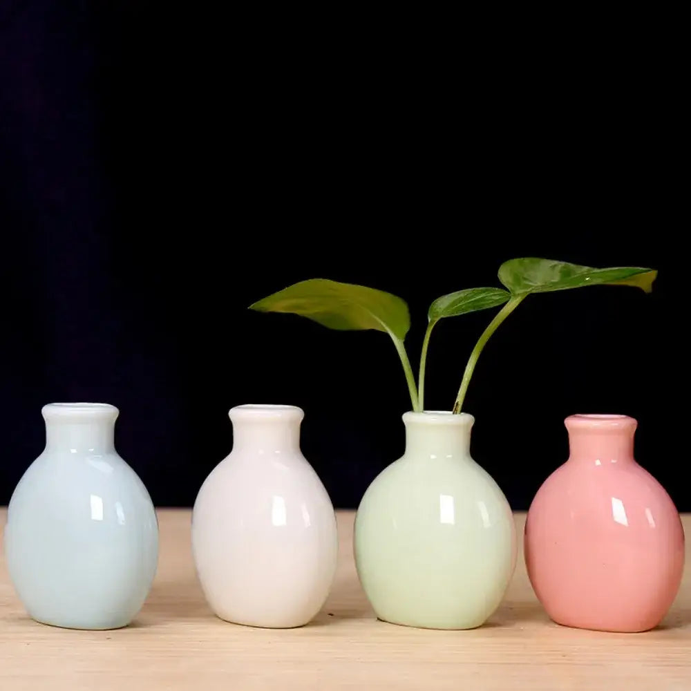 Four pastel ceramic flower vases in blue white green and pink by DecorBites™ on a wooden surface for decor use
