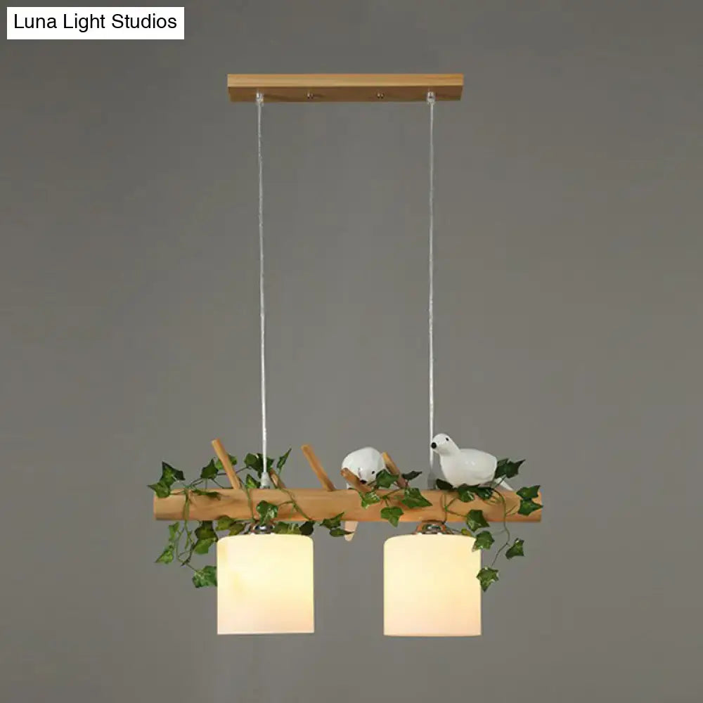Decorbites™ cylindrical milk glass pendant light with frosted shades and resin bird deco on a rustic wood branch