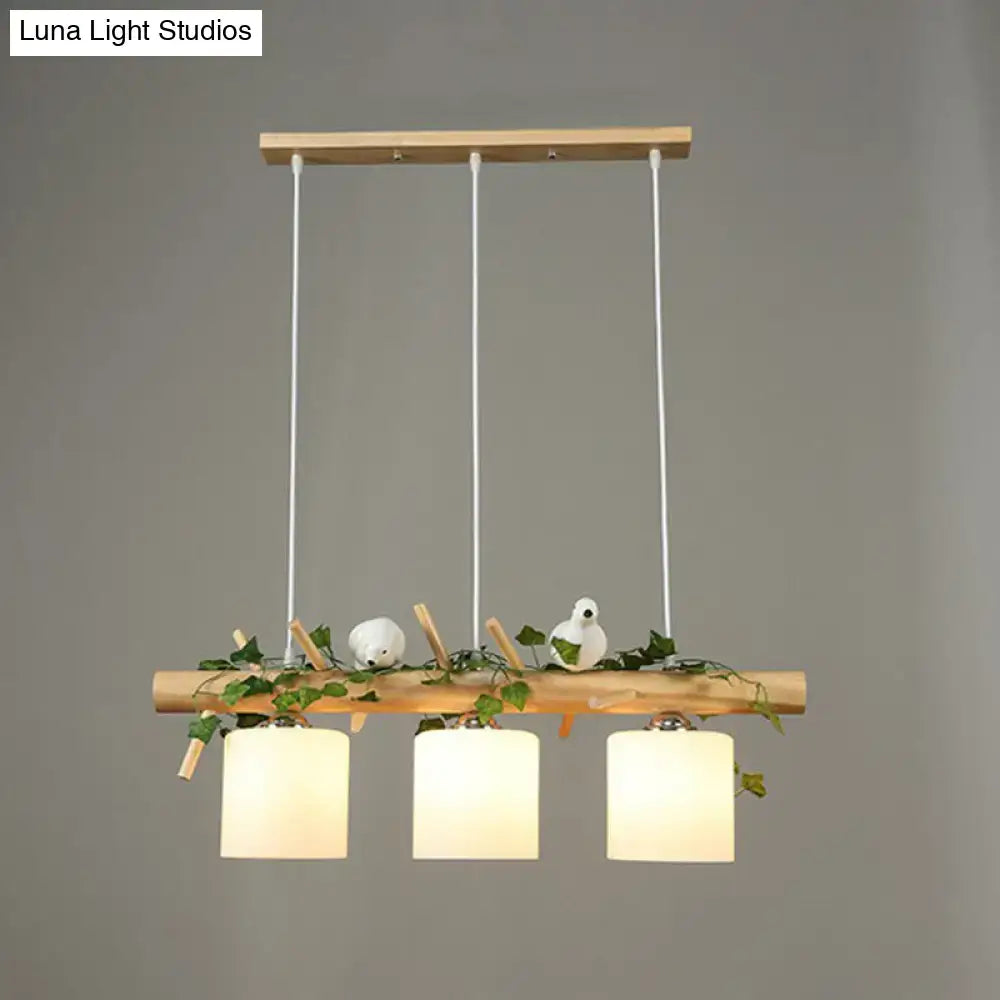 Natural wood pendant light with three cream glass shades and resin bird deco with green vines for country style restaurants