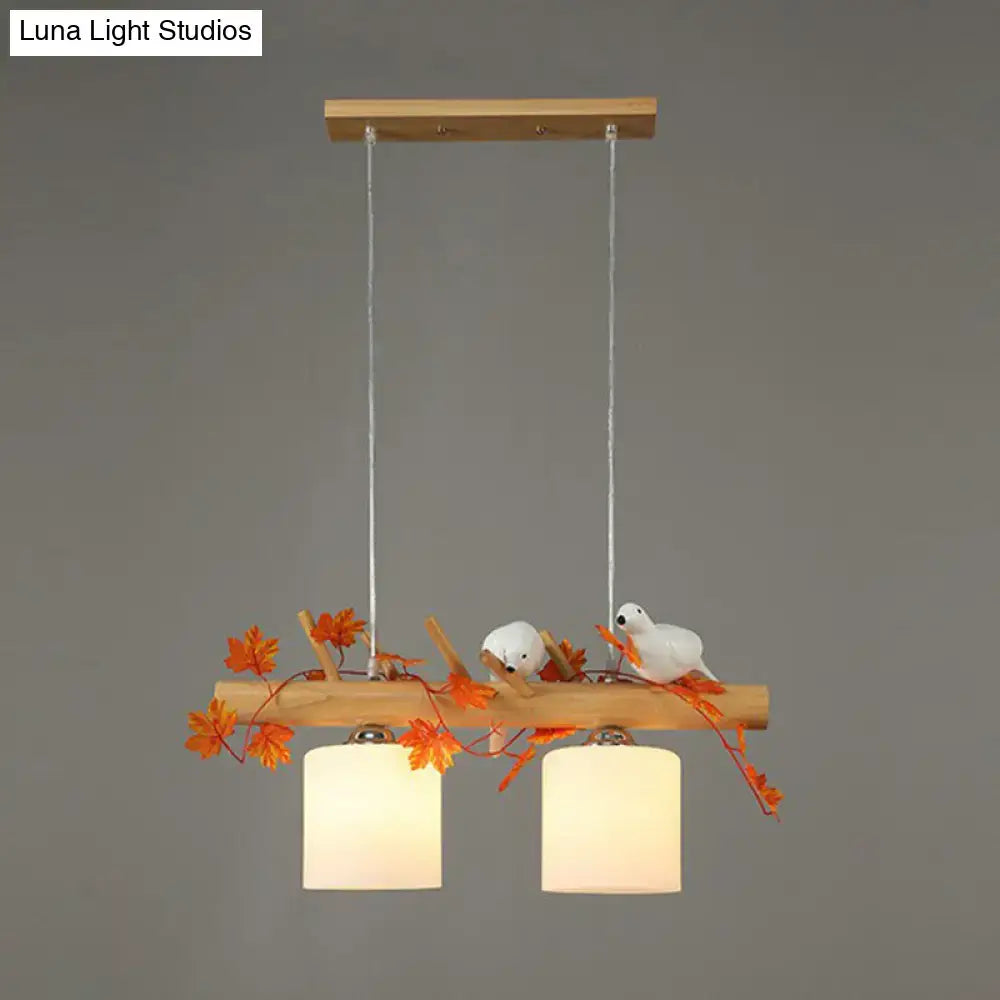 Rustic wooden pendant light with two warm cylindrical shades and resin bird deco on a natural wood branch for country style