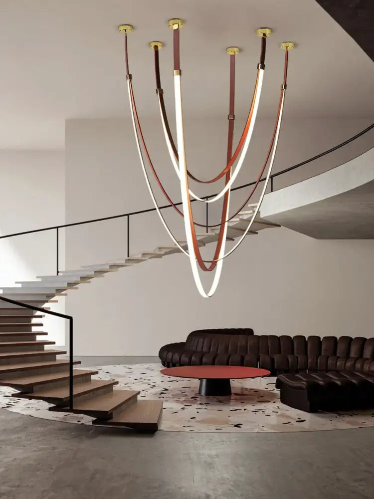 A modern DecorBites diy chandelier with flexible leather belt straps in brown and cream and illuminated curved light tubes