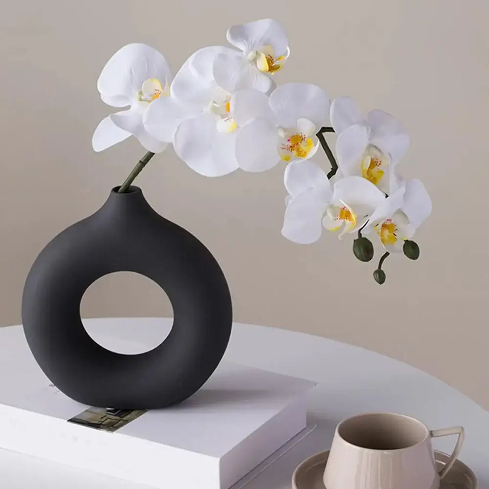Black matte ceramic donut shape flower vase holding white orchids from decorbites minimalist collection