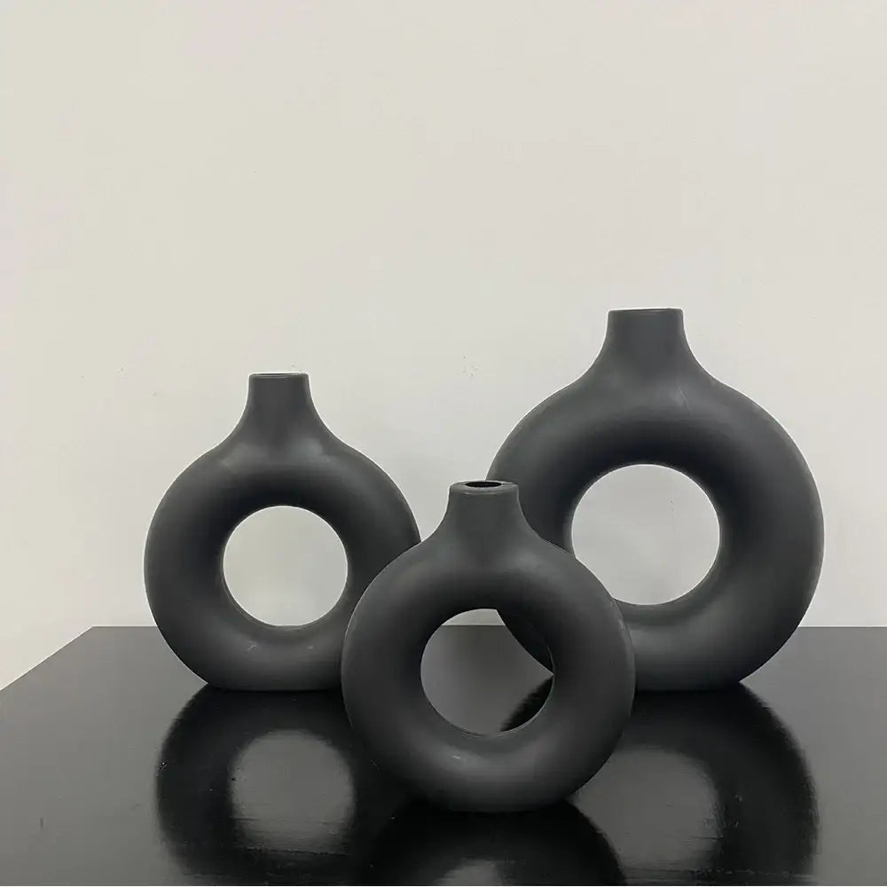 Set of three matte black ceramic flower vases with donut shape openings and smooth rounded forms by decorbites