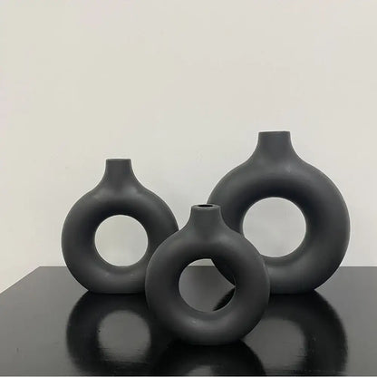 Set of three matte black ceramic flower vases with donut shape openings and smooth rounded forms by decorbites