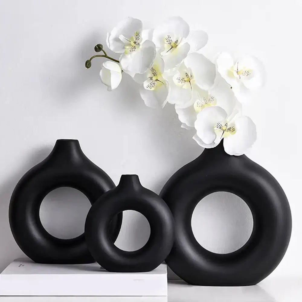 Set of three black ceramic donut shape flower vases with circular cutouts and a matte minimalist design by DecorBites™