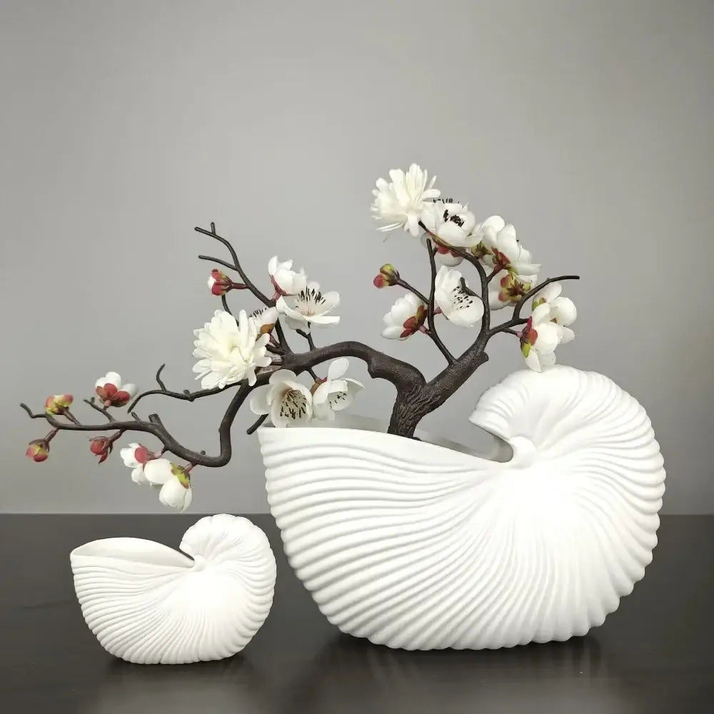 Decorbites™ elegant ceramic vase with shell conch design in white holding artificial white blossoms with ribbed texture