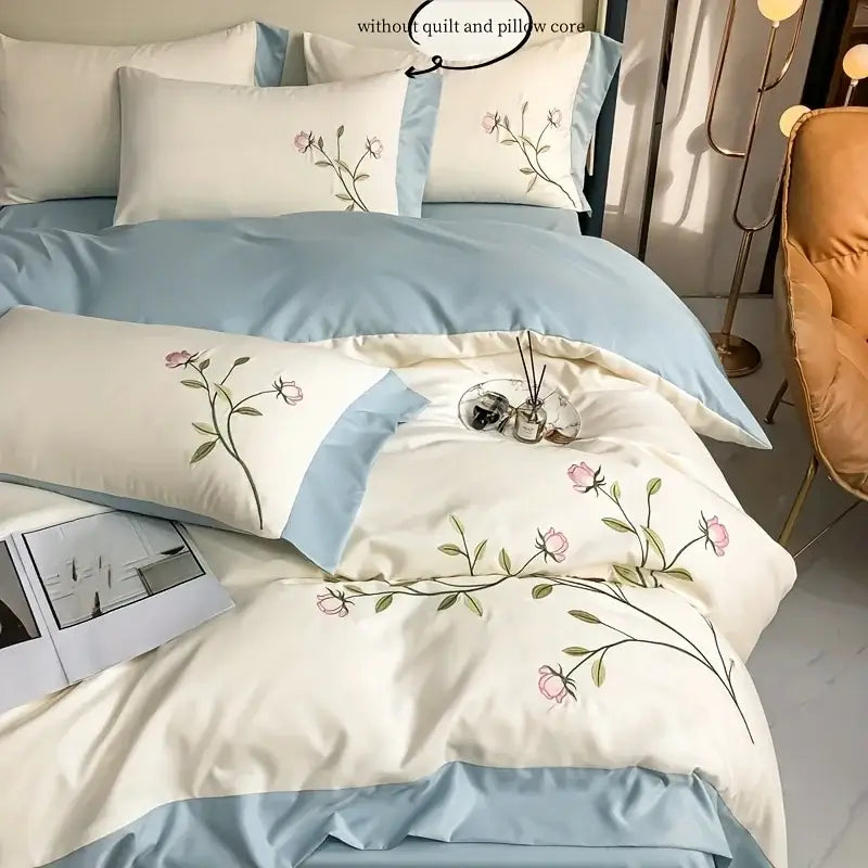 Cream-colored duvet cover with delicate pink rose embroidery and light blue satin piping from decorbites elegant embroidery set