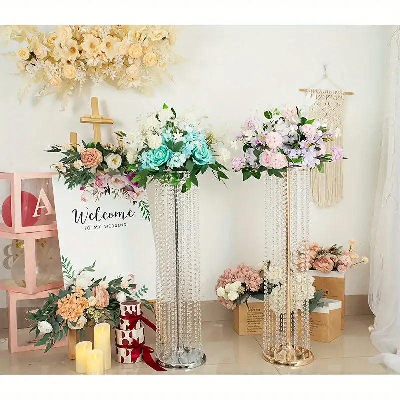 Two tall slender elegant metal vases by decorbites with crystal accents hold pastel artificial flowers for wedding decor
