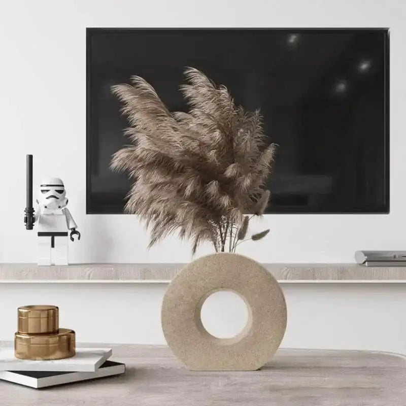 Beige circular stone donut vase holding tall feathery pampas grass for elegant nordic home decor