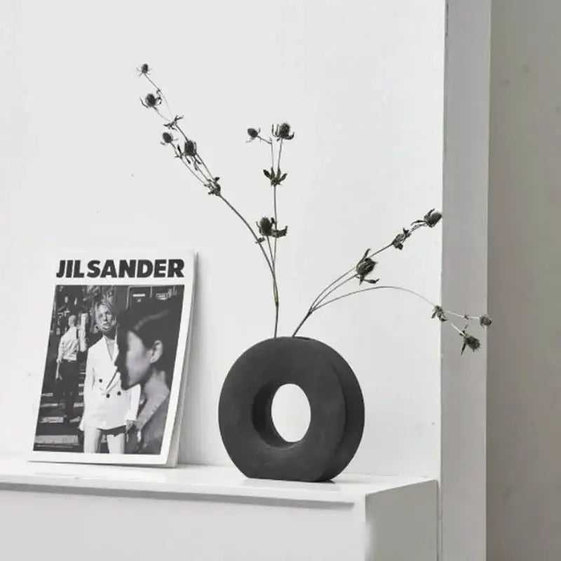 Black circular donut flower vase with central hole holding dried flowers for elegant nordic home decor