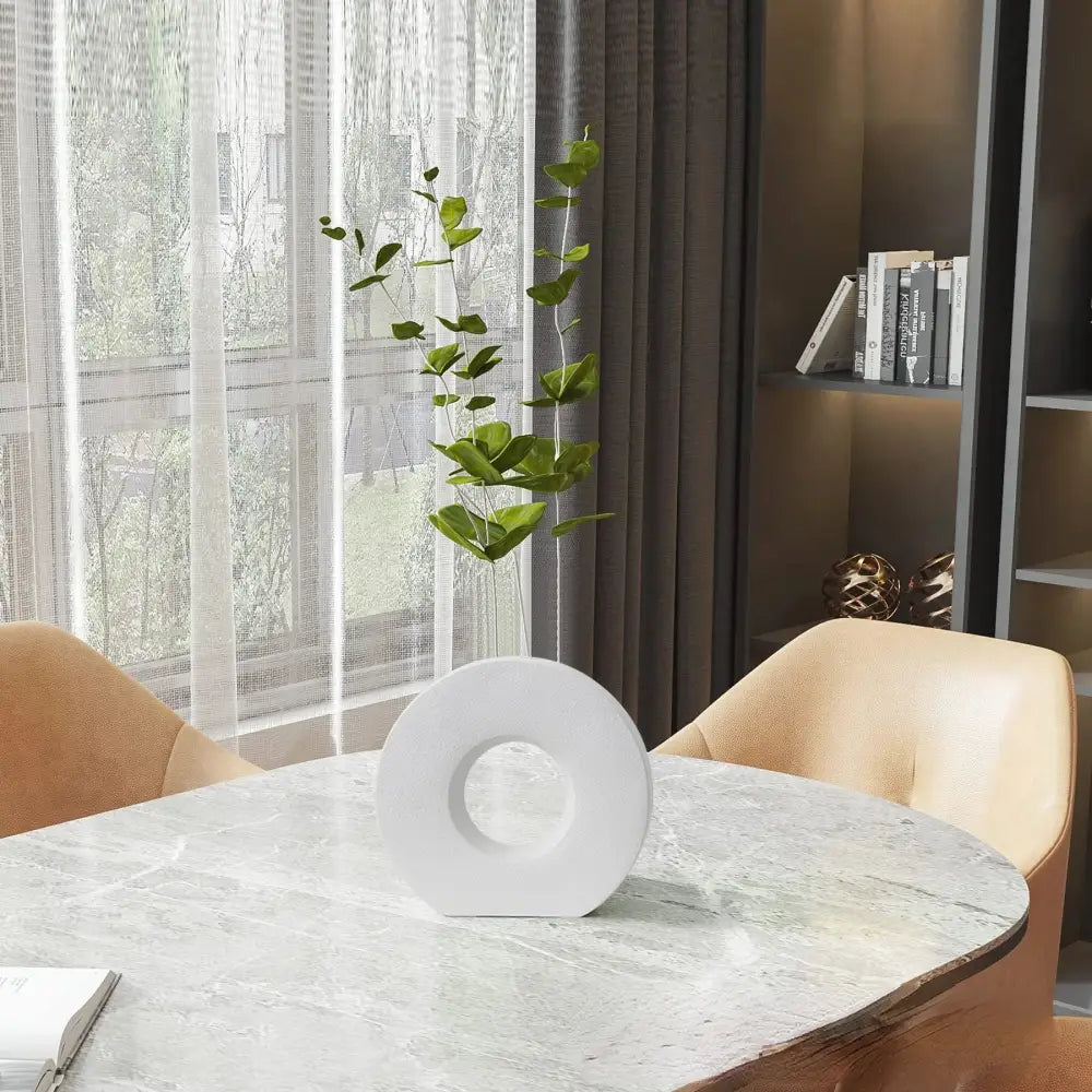 White ceramic donut vase with central hole holding green foliage for elegant nordic home decor flower vase