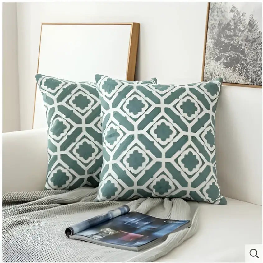 Two teal and white geometric patterned decorbites embroidered blue cotton cushion covers with soft textured fabric finish