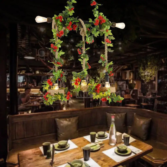 Rustic black metal island light pendant with five Edison bulbs, rope detail, and red roses draped over birdcages