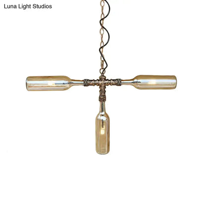A rustic cross-shaped pendant light with three amber glass bottles in aged silver black for farmhouse decor