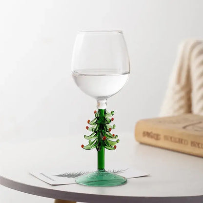 A clear glass wine goblet with a green christmas tree stem and red ornaments from DecorBites christmas wine glasses