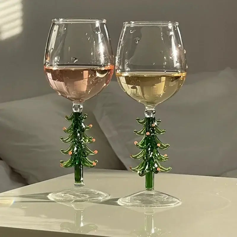 Two festive green glass christmas wine glasses with christmas tree stems and pink ornaments for holiday parties