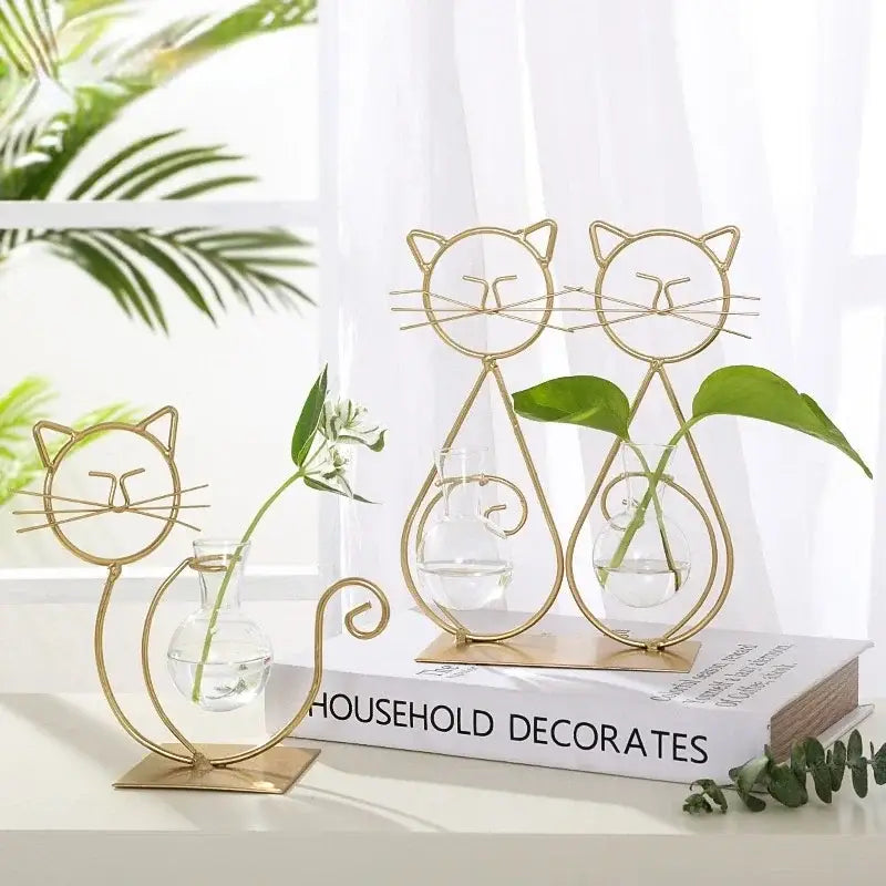 Gold wireframe cat-shaped metal vase with clear glass interior holding small plants for DecorBites home decor