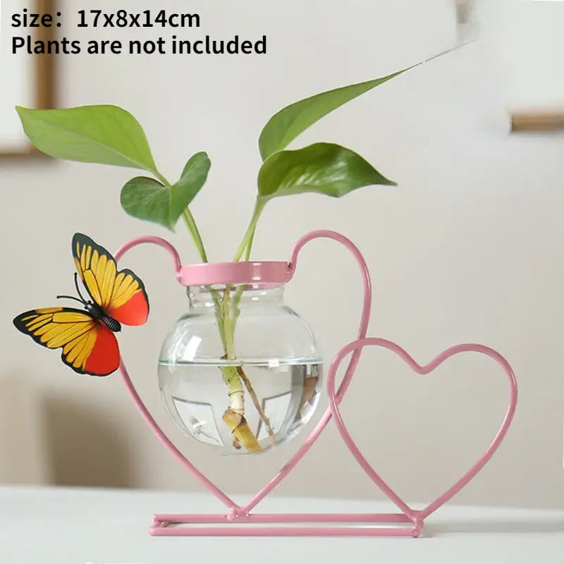 Pink heart-shaped metal vase holding clear glass sphere with green plant stems for home decor flamingo metal vase