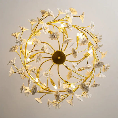 Golden chandelier with delicate french white flower ceramic branches from a central circular base for romantic home décor