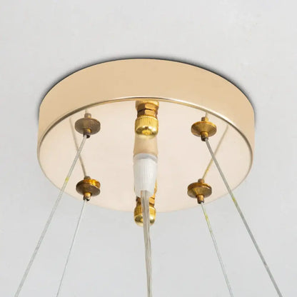 Gold-toned circular ceiling light fixture with brass hardware and clear cables for the french white flower chandelier decorbites