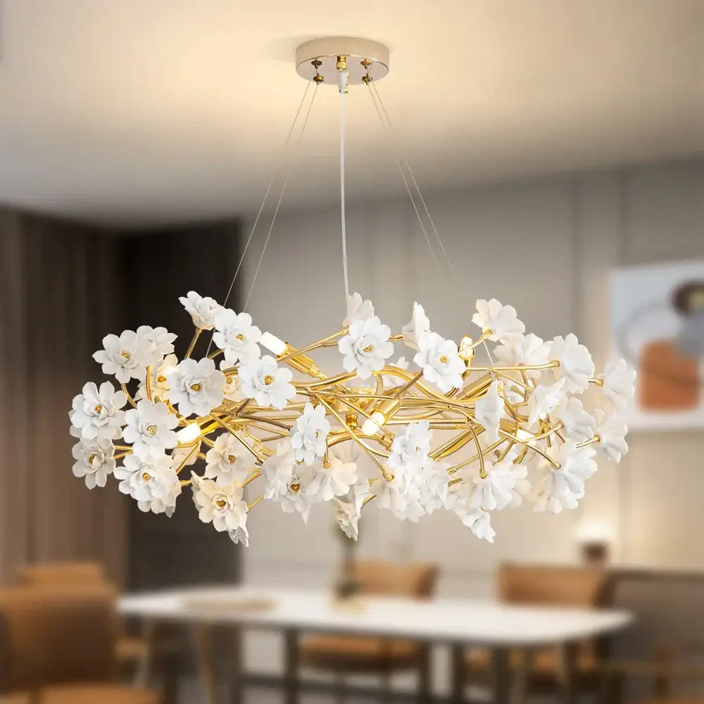 Elegant french white flower chandelier by DecorBites featuring white ceramic flowers and gold-toned metal branches with bulbs
